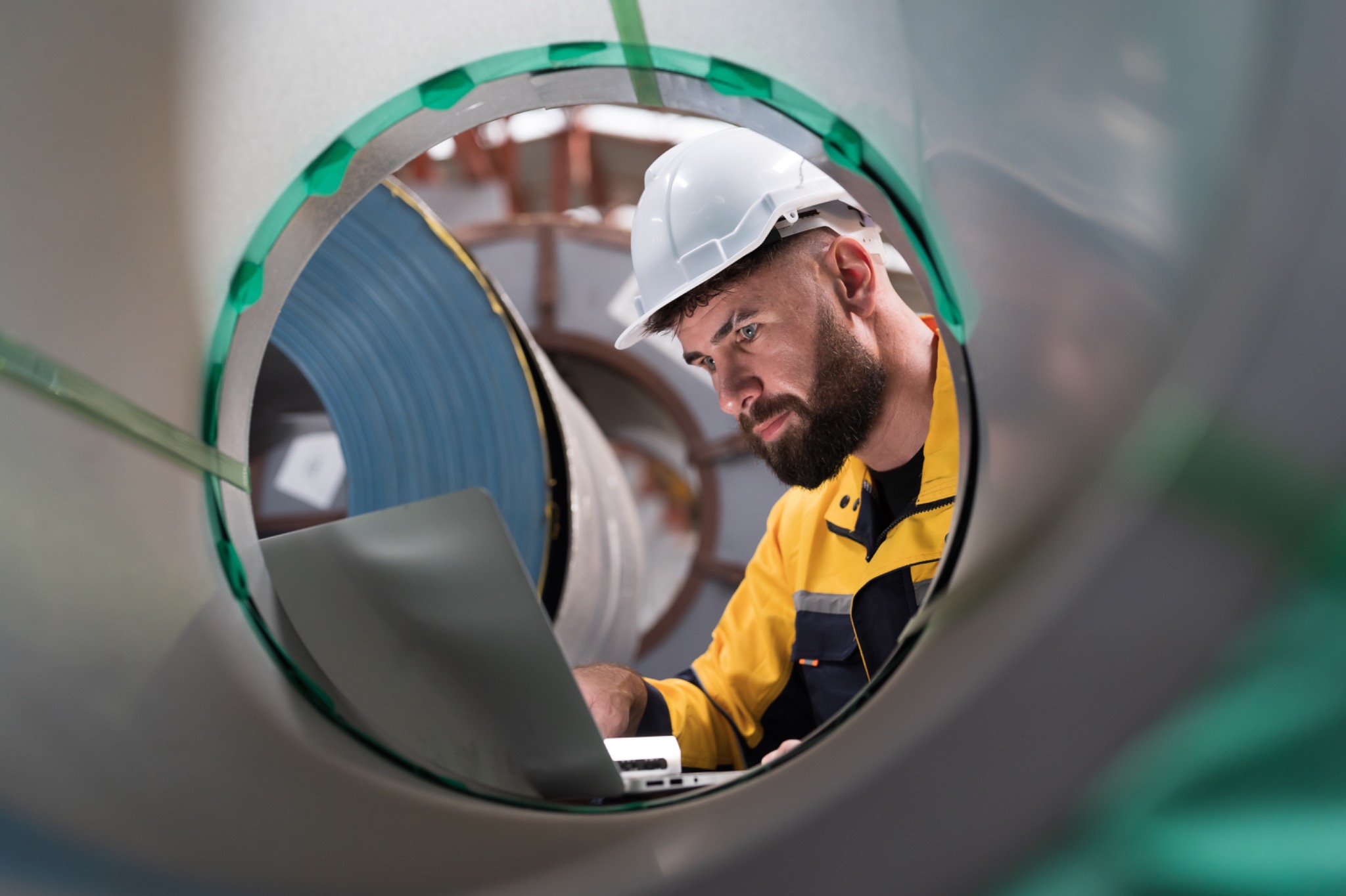 Técnico con un portátil revisando una máquina industrial.